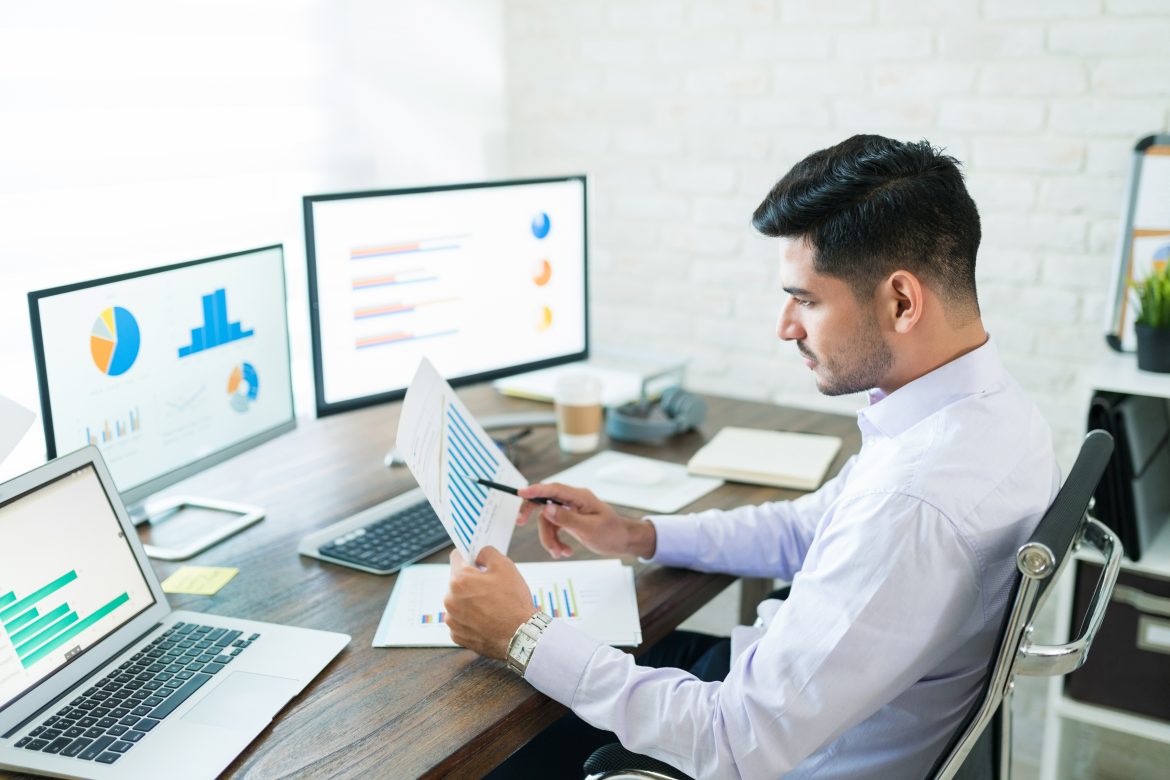 Attractive Young Male Sales Professional Analyzing Chart software akuntansi